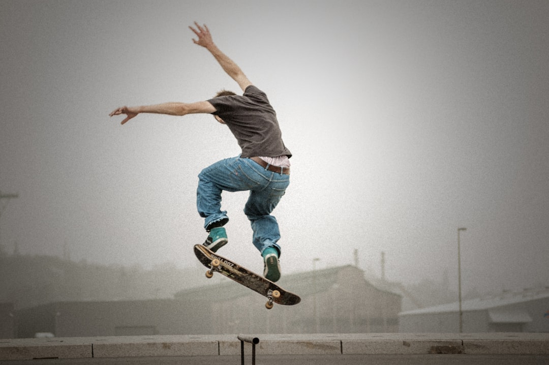 man wearing grey shirt doing skateboard tricks on air