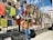 A smiling traveler standing in front of a colorful Bhutanese monastery with prayer flags fluttering in the breeze.