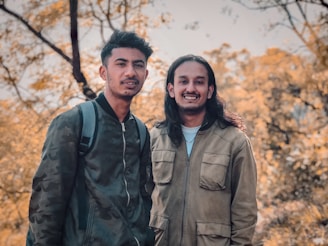 Jami and Kim smiling together on a mountain trail surrounded by autumn foliage