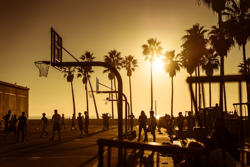 silhouette photo of people in basketball court during golden hour
