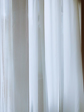 Striped door curtain gently swaying in a sunlit room, adding a touch of pattern and privacy.