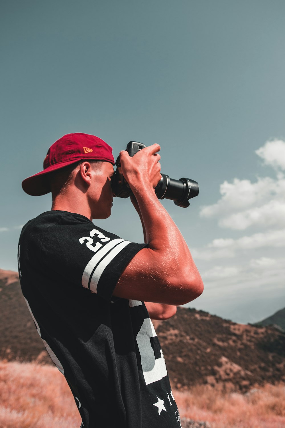 man using DSLR camera outdoors during daytime