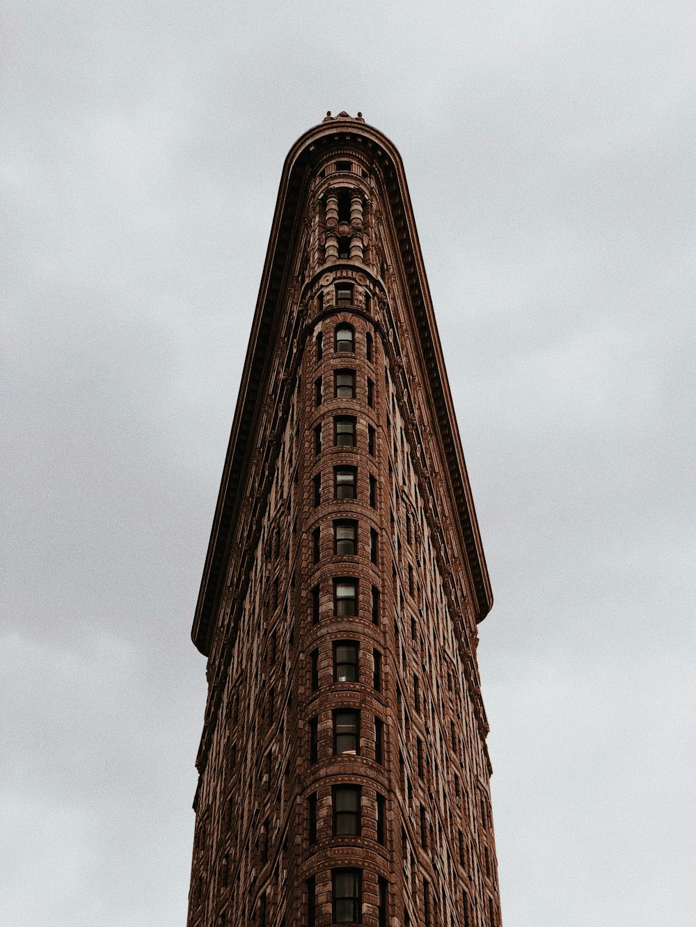 tall triangular shaped brown brick building under grey sky