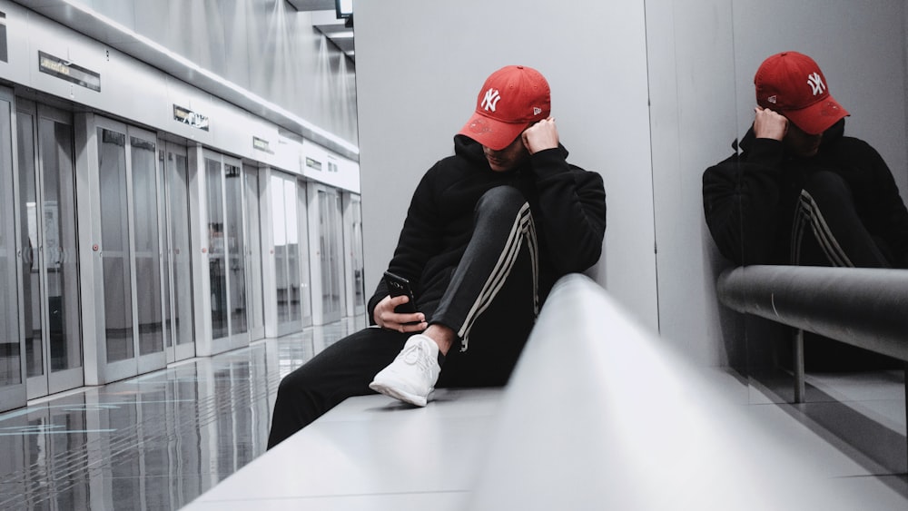 man sitting on corner while leaning on wall \