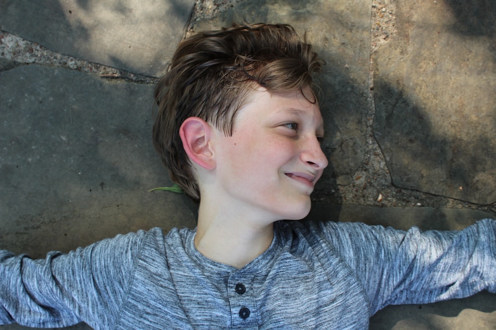 boy lying on concrete pavement smiling