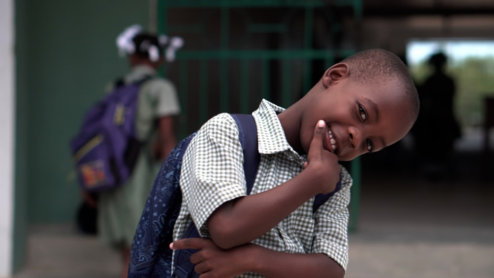 smiling boy with right hand on chin