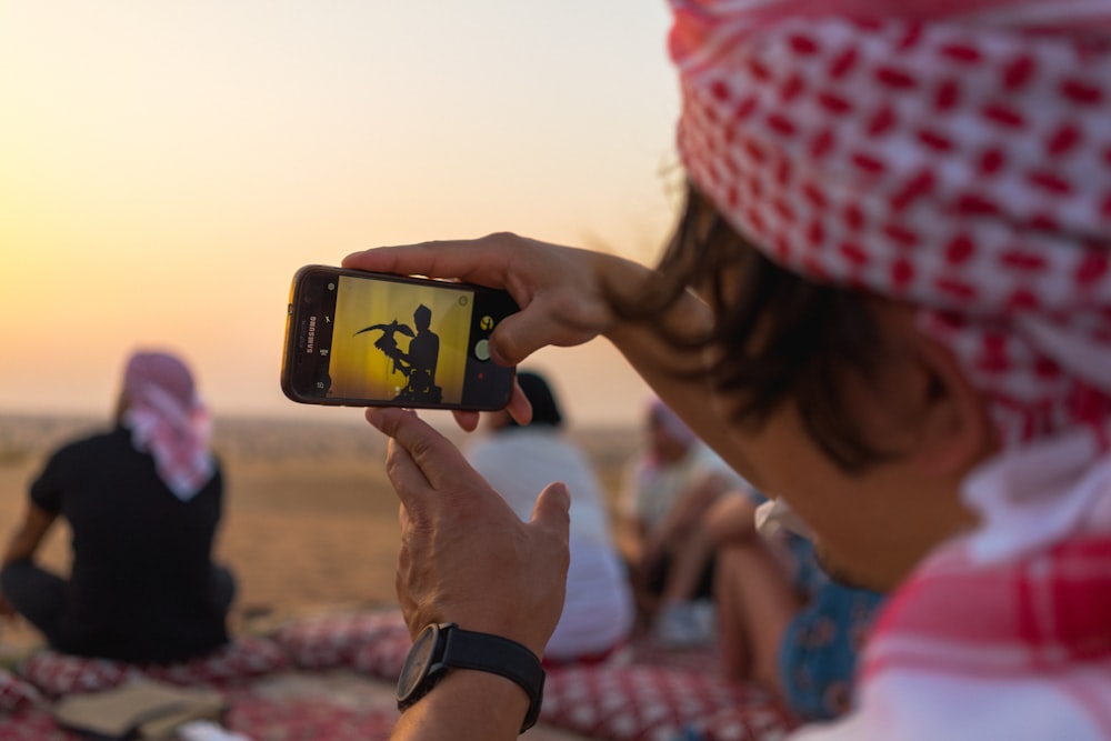 woman in red and white knit cap holding black smartphone