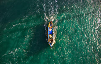 Fishermen working together on a traditional boat near a vibrant coral reef