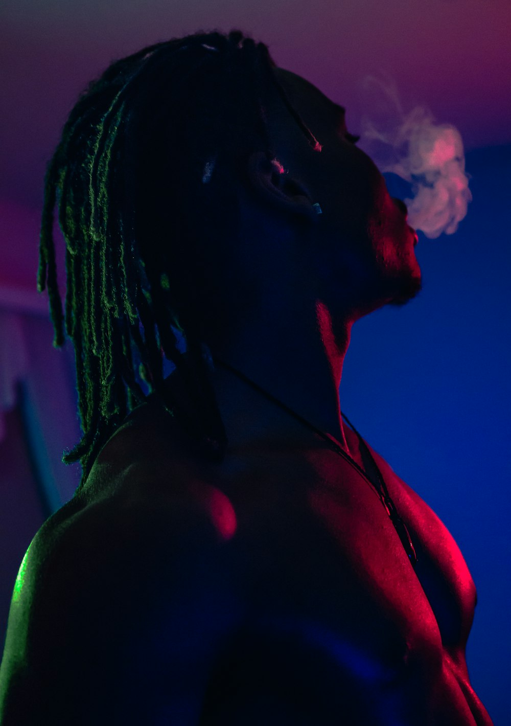 topless man smoking inside dark room