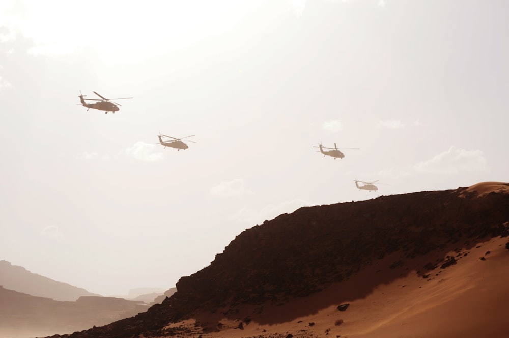 four helicopters over mountain at daytime