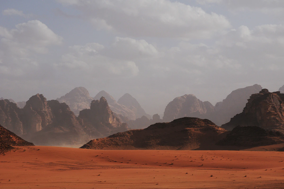 A figure walking the crest of an apricot dune in the Sahara at sunset.
