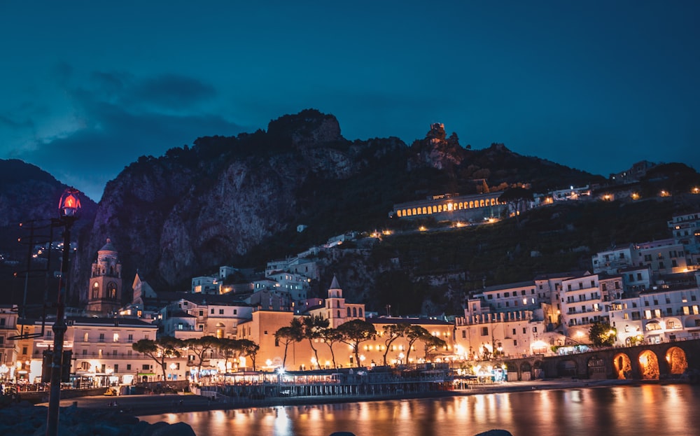 lighted city buildings near mountains during nighttime