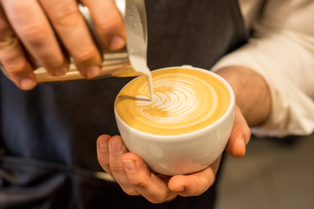 person pouring cream on coffee