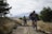 Two cyclists riding mountain bikes along a rugged trail surrounded by desert vegetation.