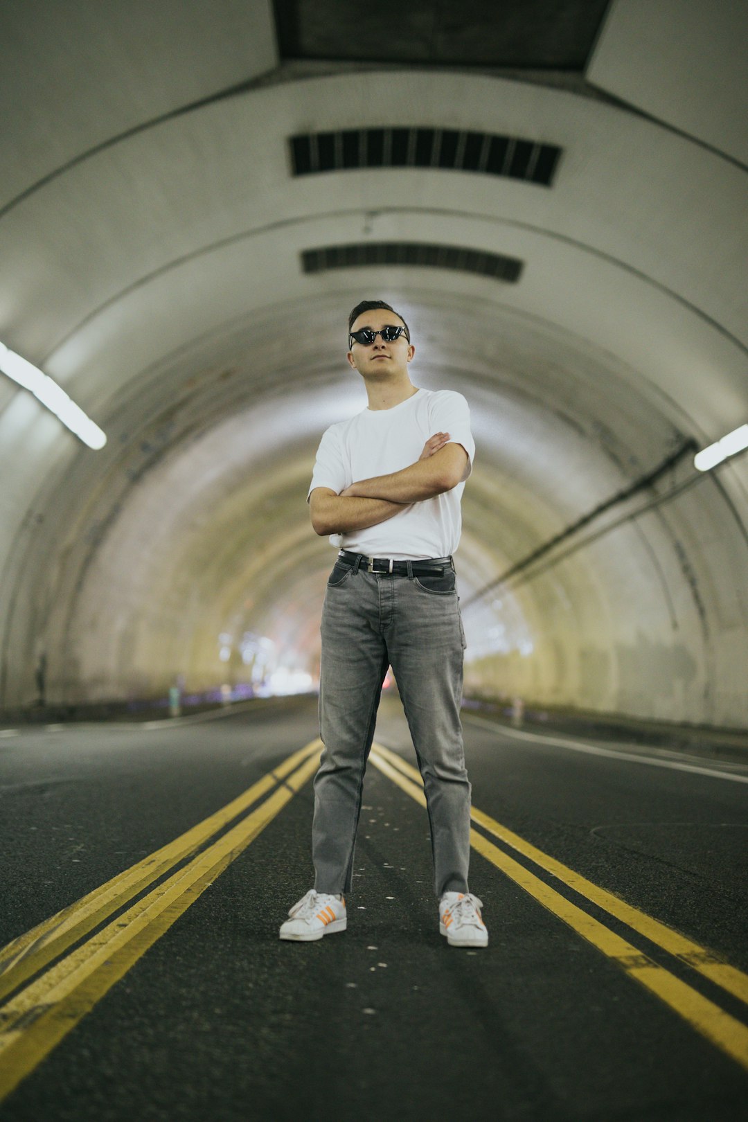 man wearing white shirt standing inside tunnel