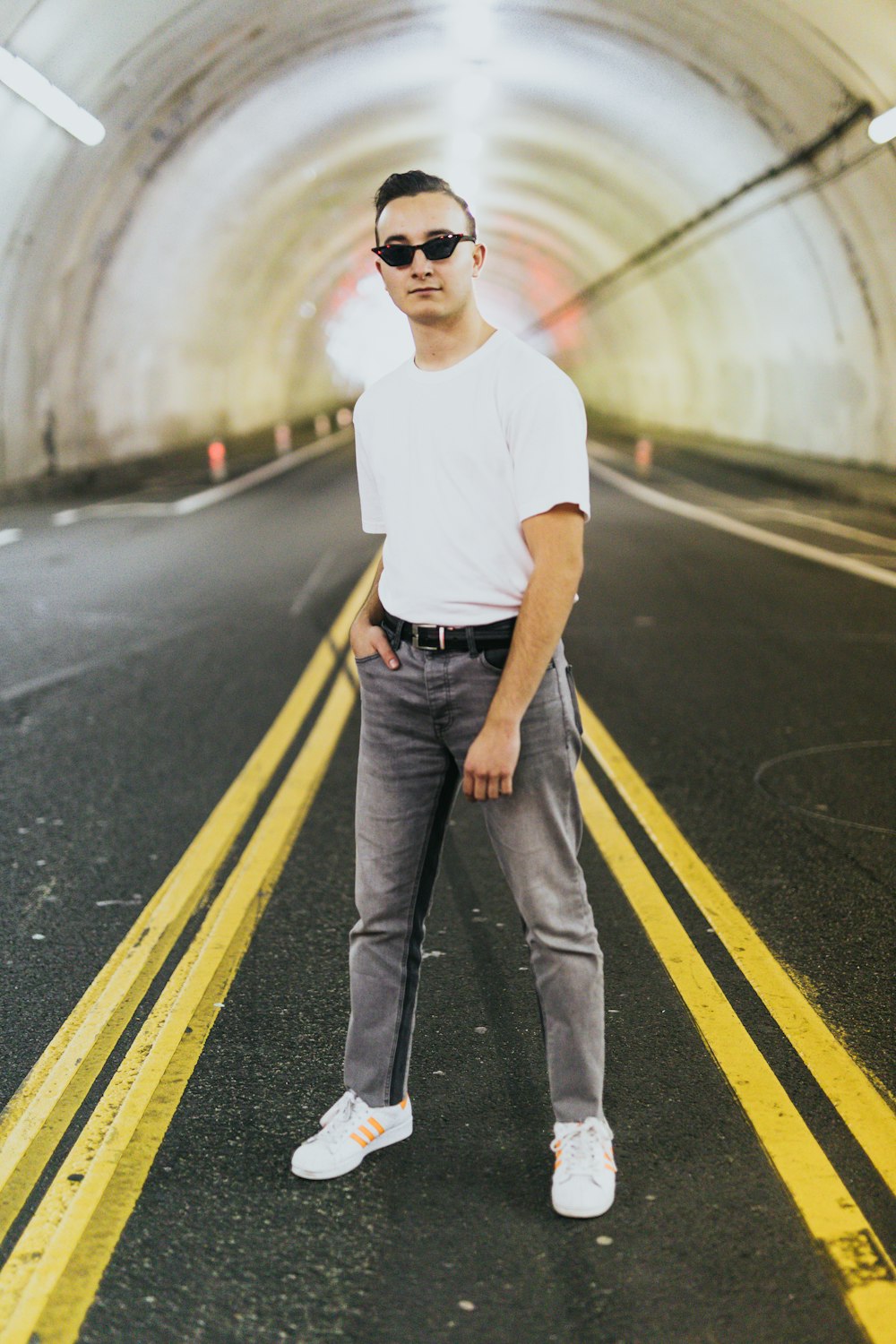 man wearing white crew-neck shirt standing on roadway