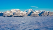 A breathtaking aerial shot of snow-capped mountains under a clear blue sky.