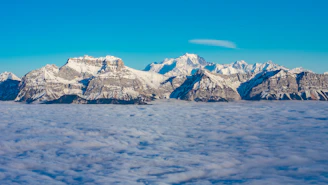 A breathtaking view of snow-capped mountains and lush green valleys in northern Pakistan under a clear blue sky.