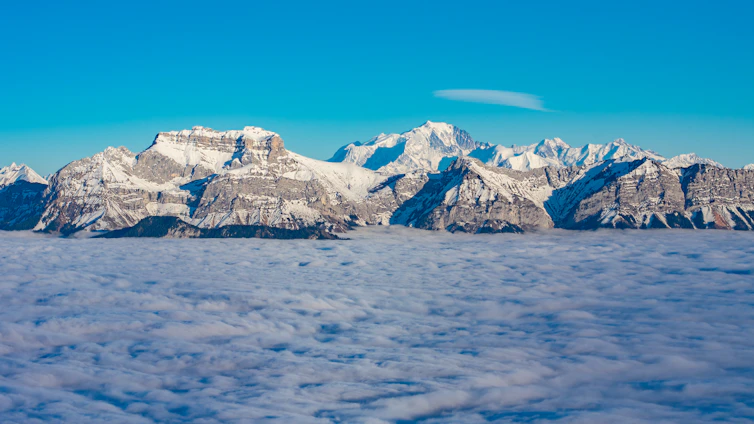 A breathtaking view of snow-capped mountains and lush green valleys in northern Pakistan under a clear blue sky.