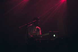 A person practicing guitar with a laptop nearby