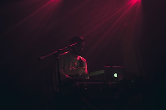 A person practicing guitar with a laptop nearby