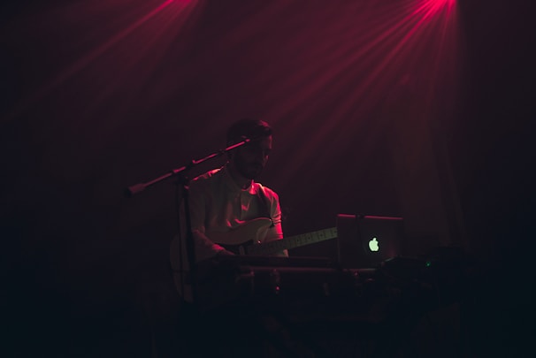 Instructor giving an online guitar lesson with a laptop.