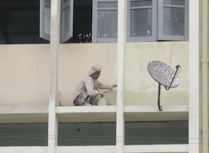A friendly professional painter working on a house exterior in Jeddah