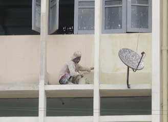Painter applying fresh coat on a commercial building’s exterior wall.