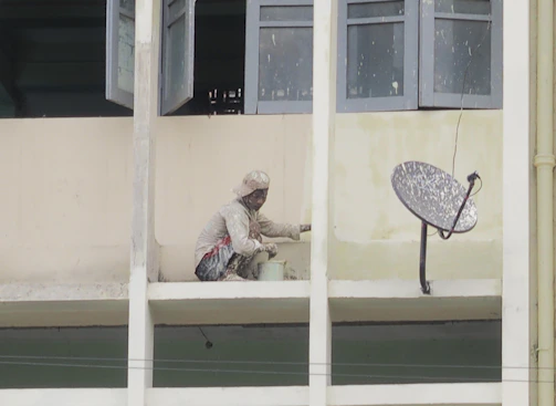 A friendly professional painter working on a house exterior in Jeddah