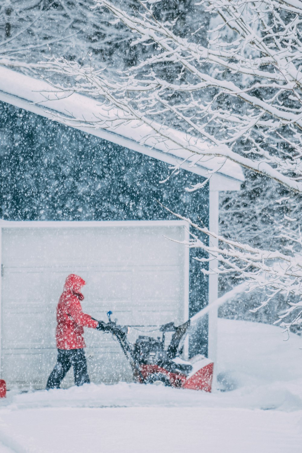 uomo che spazza la neve sul lato della casa