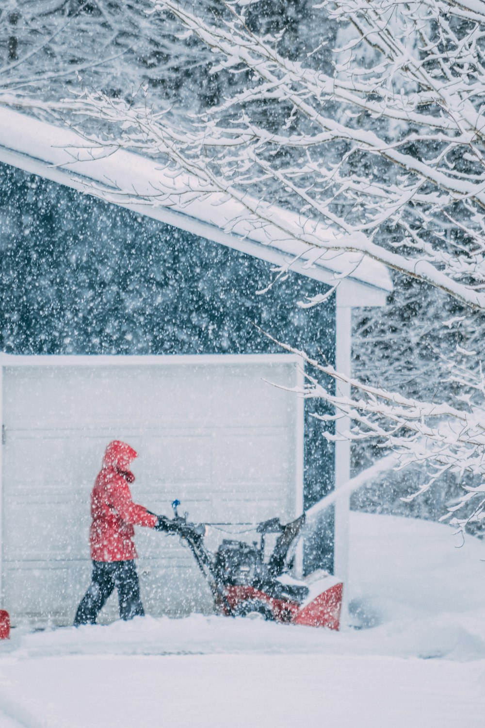 Mann pflügt Schnee an der Seite des Hauses
