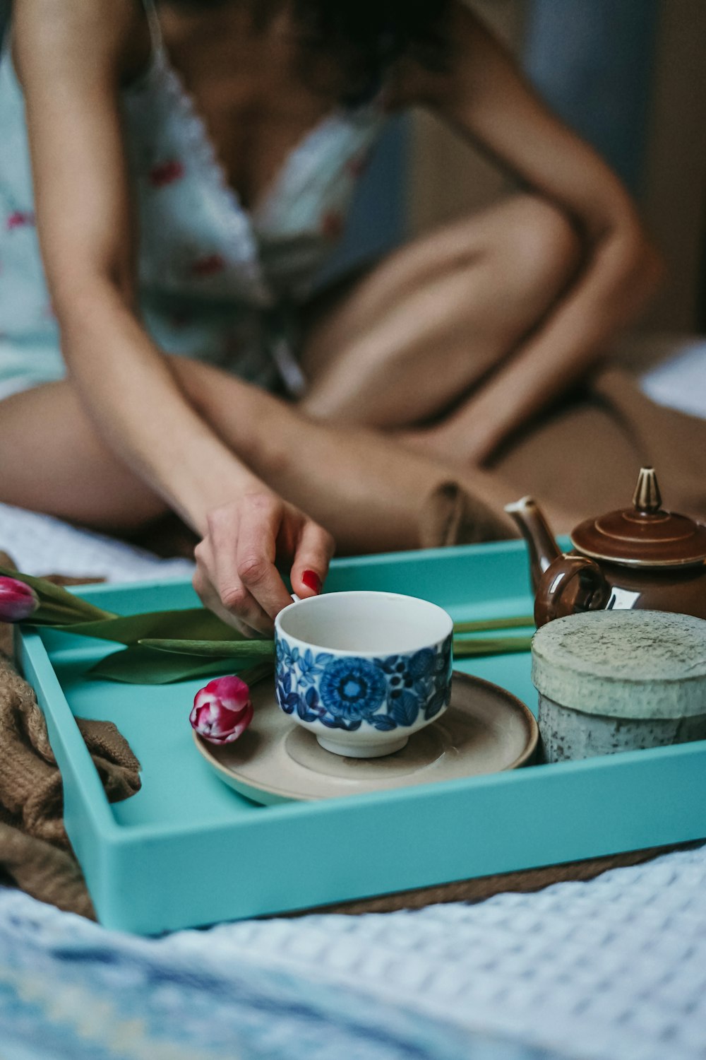 woman having cup of tea on bed