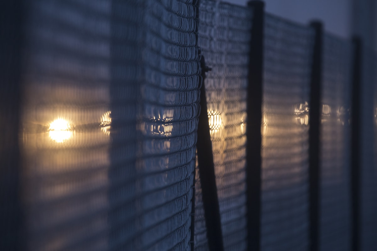 Fence at dusk with light shining through, suggesting detention but with hope ahead.