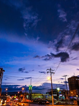 Bright blue and green electric energy flow over a modern city skyline at dusk.