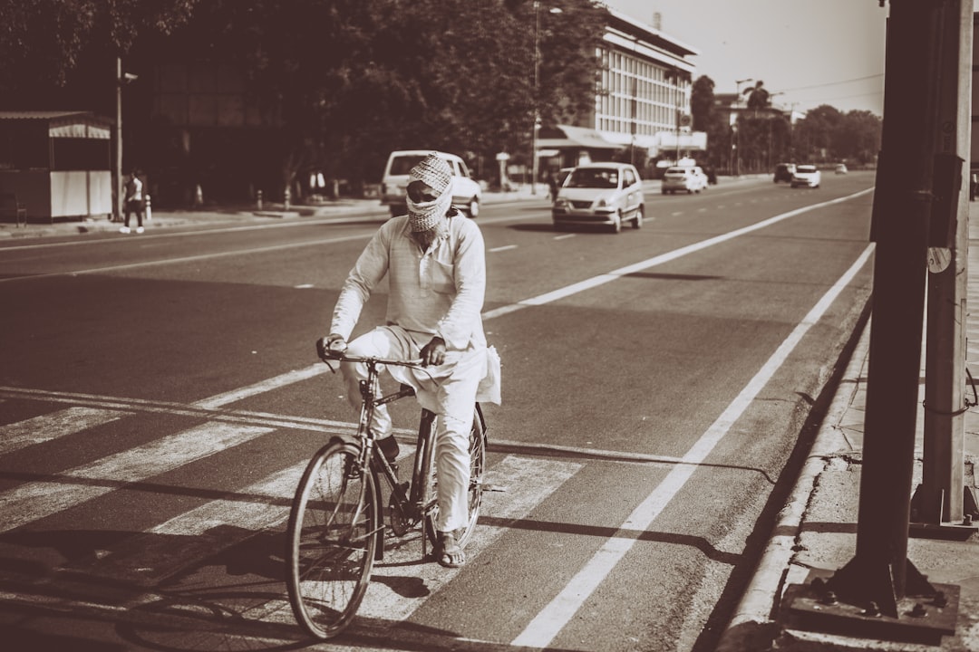 grayscale photography of man riding on bicycle