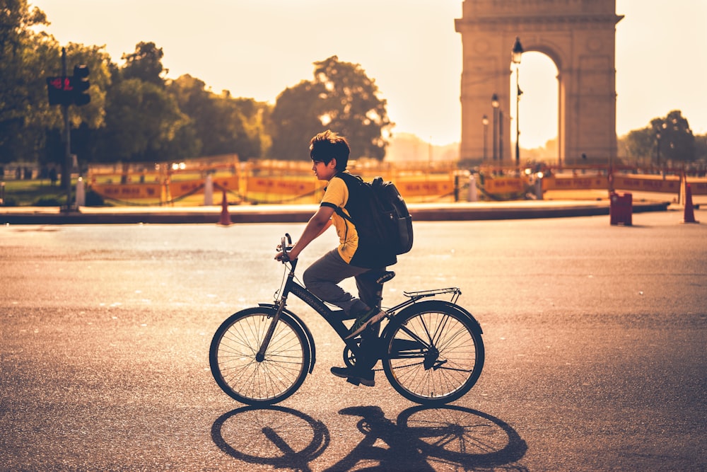 boy riding bicycle beside India gate
