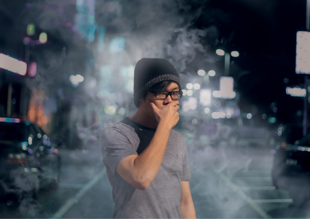 man covered his mouth surrounded by smoke