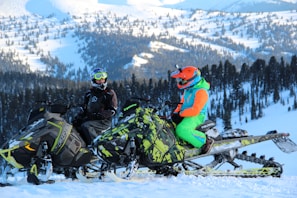 Professional guide giving safety instructions to a small group dressed in winter gear next to snowmobiles