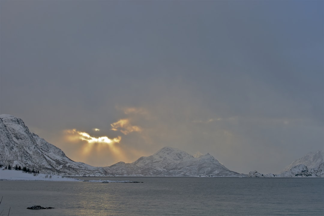 yellow sunlight passing through thick grey clouds over the snowy mountain