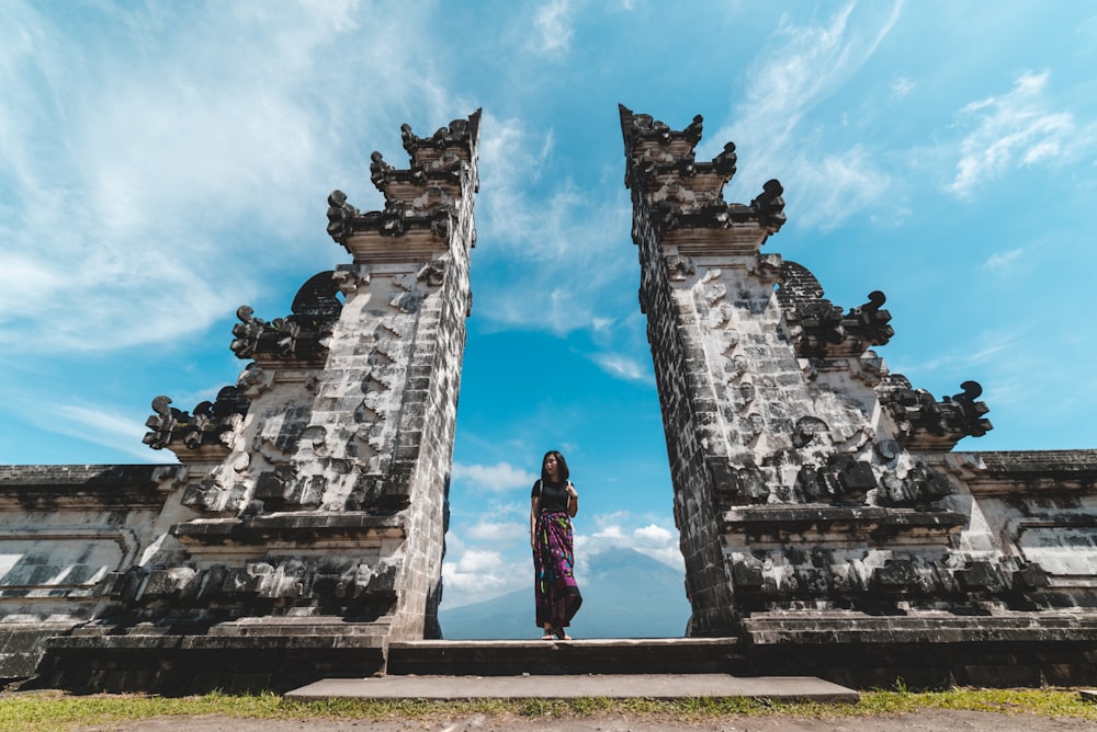 woman standing between concrete structures under blue sky