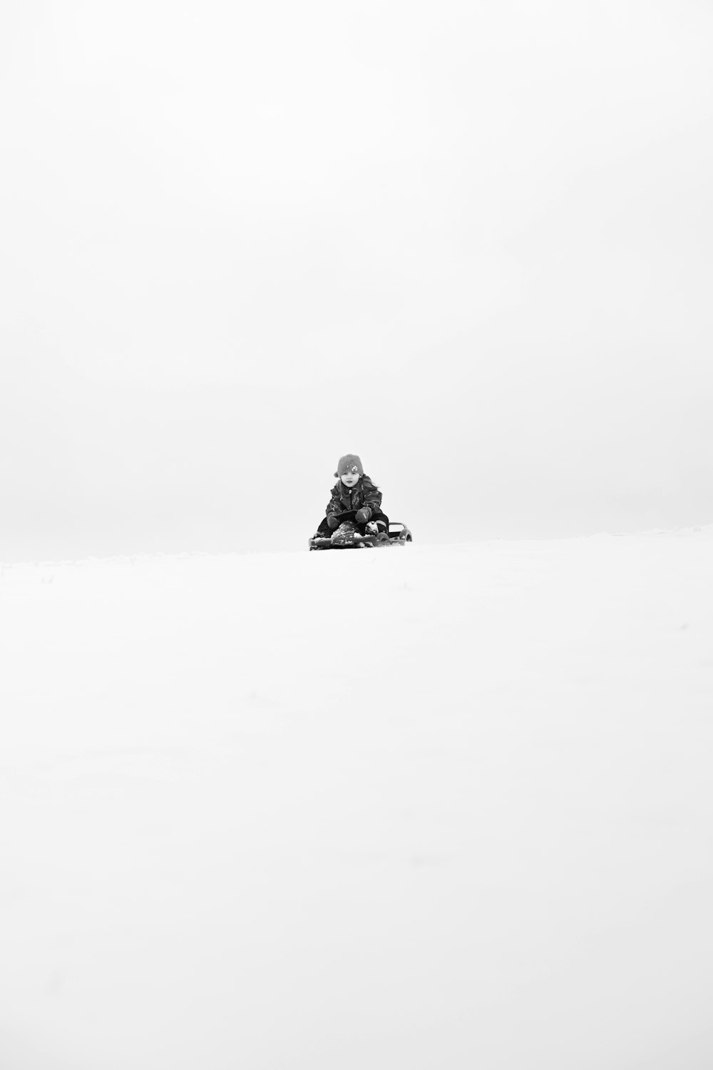 child on sled going down on snow slope