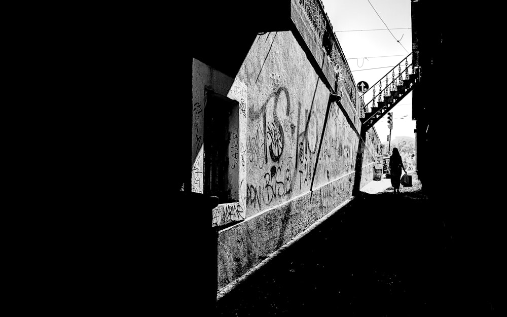 greyscale photo of person under stairs