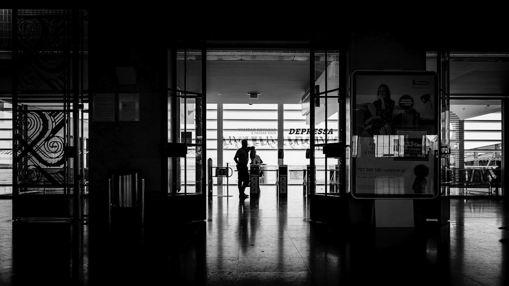 person standing on floor tiles grayscale photo