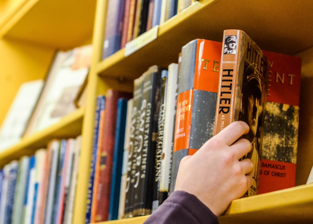 person holding book in book shelf