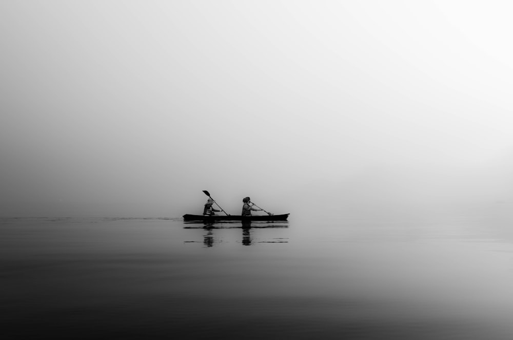 two person sailing on calm body of water