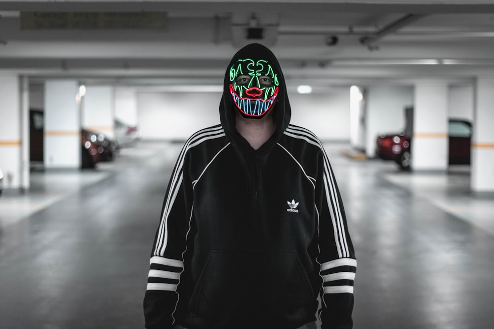 man wearing black and white adidas jacket wearing multicolored mask