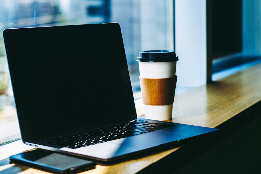 black laptop computer on brown wooden table