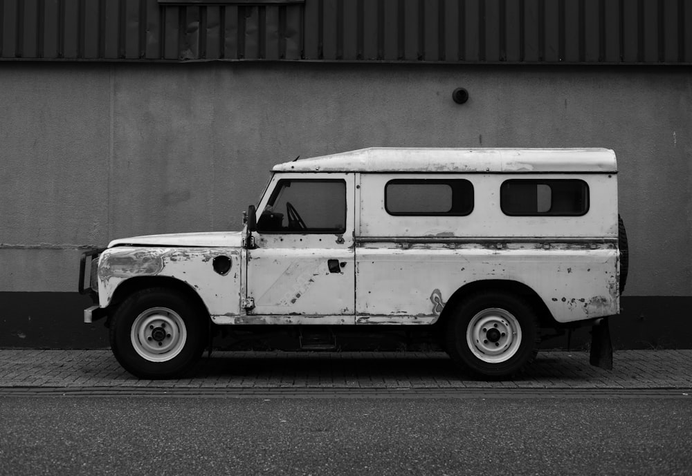 white vehicle parked beside concrete wall