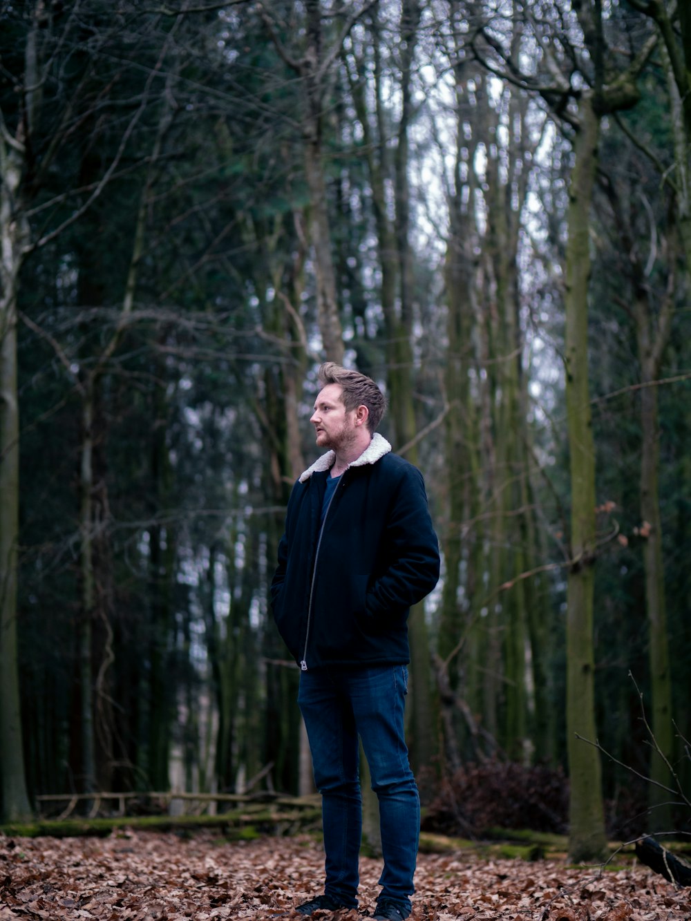 man wearing jacket standing near trees
