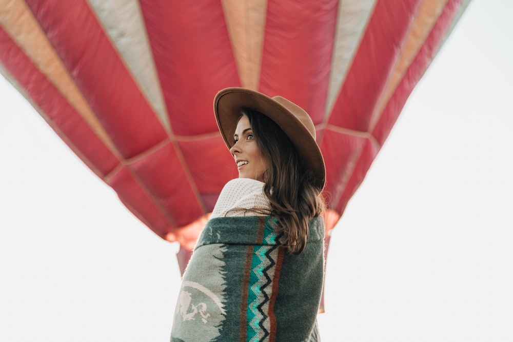 woman wearing brown hat near red hot air balloons